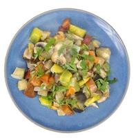 stufato di verdure di stagione brillante su piatto su sfondo bianco