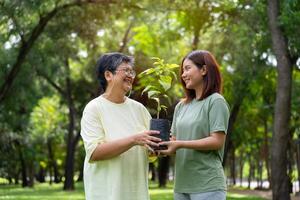 vecchio asiatico donne e figlia aderire come volontari per rimboschimento, terra conservazione attività per ridurre globale riscaldamento crescita caratteristica e prendere cura natura terra. ambiente concetto foto