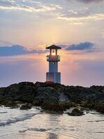 un' tranquillo paesaggio marino con un' faro silhouette contro un' vivace tramonto, Perfetto per temi di viaggio e natura foto