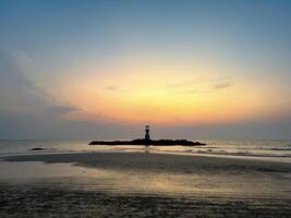 un' tranquillo paesaggio marino con un' faro silhouette contro un' vivace tramonto, Perfetto per temi di viaggio e natura foto