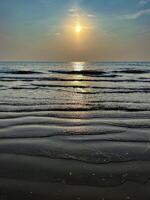 un' tranquillo oceano scena come il sole tuffi sotto il orizzonte, pittura il cielo con occhiali da sole di rosa e arancia foto