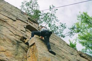 giovane atletico donna nel attrezzatura fare roccia arrampicata all'aperto. formazione la zona per all'aperto attività. estremo sport. foto