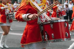 strada prestazione. avvicinamento di femmina batteristi mani nel rosso Vintage ▾ uniforme a il parata foto