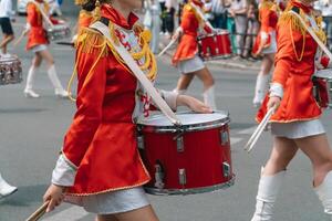 strada prestazione. avvicinamento di femmina batteristi mani nel rosso Vintage ▾ uniforme a il parata foto