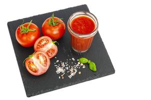 bicchiere di succo di pomodoro, pomodori rossi maturi su vassoio di pietra nera foto