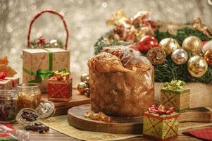 panettone, uvetta e cubetti di frutta candita su tagliere in legno con addobbi natalizi foto