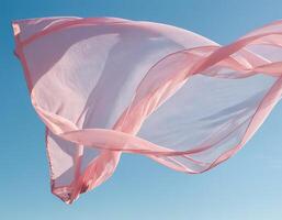 volante rosa tessuto onda su blu cielo sfondo e illuminato di luce del sole foto