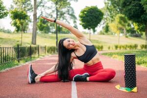 bellissimo giovane donna fare allungamento esercizio su verde erba a sport campo. yoga. salutare stile di vita concetto foto