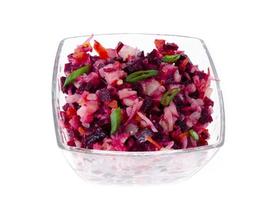 dieta vegetariana insalata di verdure con barbabietole in un'insalatiera di vetro su sfondo bianco.