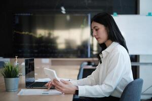 un' attività commerciale donna contabile o banchiere fa un revisione e calcola spese per un' finanziario rapporto equilibrio foglio dichiarazione utilizzando un' calcolatrice. il principio di Salvataggio e investire. foto