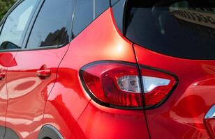 avvicinamento di posteriore leggero su rosso auto cattura parcheggiata nel il strada. selettivo messa a fuoco foto