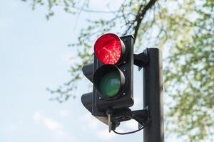 avvicinamento di rosso traffico leggero per macchine con un' blu cielo nel il sfondo. foto