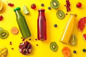 bottiglie con succo sano, frutta e verdura su sfondo colorato foto
