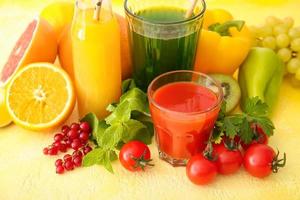 bicchieri con succo sano, frutta e verdura su sfondo colorato foto