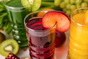 bicchieri con succo sano, frutta e verdura su sfondo chiaro foto