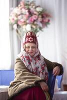 un' bellissimo anziano russo donna signora nel il nazionale copricapo kokoshnik e pelle di pecora cappotto sorrisi e sembra a il telecamera. foto