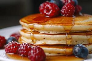 soffice Pancakes piovigginato con acero sciroppo e sormontato con fresco frutti di bosco. foto