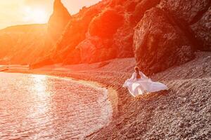 misterioso donna silhouette lungo capelli passeggiate su il spiaggia oceano acqua, mare ninfa vento ascolta per il onda. lanci su un' lungo bianca vestire, un' divine tramonto. artistico foto a partire dal il indietro senza un' viso