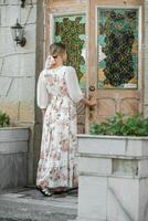 un' donna nel un' fiore vestito si apre il porta per il Casa foto