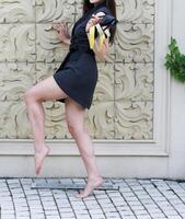 un' sexy ragazza con lungo gambe nel alla moda, corto gonna e nero alto tacchi in posa all'aperto su marciapiede. foto