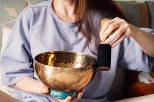 un' sereno donna pratiche suono guarigione utilizzando un' cantando ciotola, immersa nel un' momento di meditativo foto