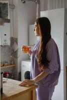 donna guardando fuori dalla finestra della cucina foto