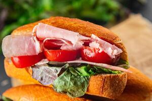Sandwich prosciutto, pomodoro, verde lattuga mangiare cucinando aperitivo pasto cibo merenda su il tavolo copia spazio cibo sfondo rustico foto