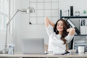 rilassato professionale donna prende un' rompere per allungare a sua postazione di lavoro, segnalazione un' momento di meritato riposo nel sua occupato giorno. foto