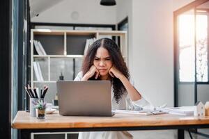 stressato giovane professionale accigliato a sua il computer portatile schermo, un' cartello di il sfide di un' esigente giornata lavorativa. foto