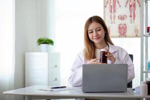 giovane donna Asia medico con stetoscopio utilizzando computer il computer portatile parlando conferenza chiamata con paziente a scrivania nel Salute clinica o Ospedale. consulenza e terapia concetto foto