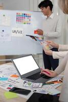 progettista squadra raccomanda colore mentre modello il computer portatile Schermo ui e UX disegni per mobile App e sito web. creativo design e attività commerciale concetto foto
