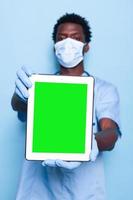 assistente medico che tiene lo schermo verde verticale sul tablet foto
