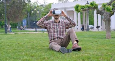 il giovane uomo d'affari maschio nel parco estivo usa le cuffie per la realtà virtuale foto