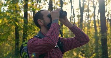 ritratto di giovane viaggiatore maschio con il binocolo nella foresta foto