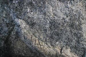 fondo grigio grezzo di struttura della roccia del granito. frammento di muro di pietra naturale foto