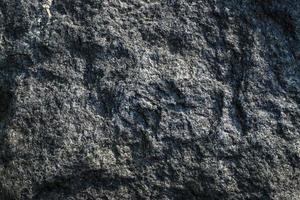 fondo grigio grezzo di struttura della roccia del granito. frammento di muro di pietra naturale. incrinato, fondale. foto