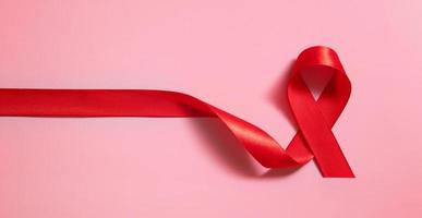 simbolo del nastro rosso della giornata mondiale contro l'AIDS su sfondo rosa in formato banner foto