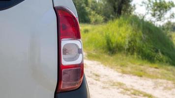 faro posteriore destro. la parte posteriore di una piccola berlina per passeggeri o suv di un'auto bianca con un gruppo di luci posteriori e una parte del cofano del bagagliaio a destra. Indicatore di direzione rosso e luce di stop. foto