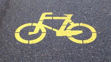 simbolo della bicicletta che rappresenta un percorso per le biciclette. cartello verniciato giallo per biciclette sull'asfalto. piatto, vista dall'alto. foto