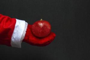 concetto di festa. nella mano del melograno succoso di babbo natale su sfondo nero. foto