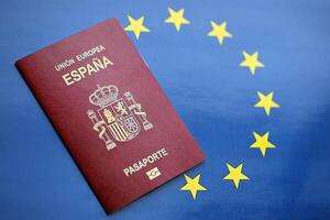 rosso spagnolo passaporto di europeo unione su blu bandiera sfondo vicino su foto