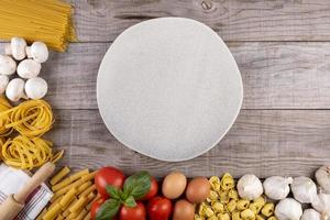 pasta, verdure, uova, con piatto al centro su tavola di legno foto