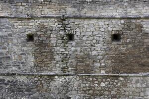 molto vecchio mattone pietra parete di castello o fortezza di 18 ° secolo. pieno telaio parete con obsoleto sporco e Cracked mattoni foto