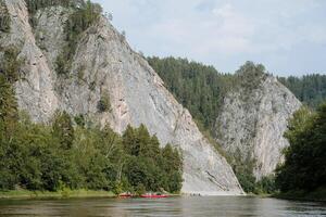 persone zattera su catamarani su un' montagna fiume, un' vacanza su un' acqua viaggio, rocce appendere al di sopra di il acqua, il grigio colore di il montagne. foto