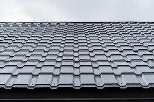 metallo piastrelle avvicinamento, grigio dipingere su il tetto di il Casa, nuovo costruzione di il superiore pavimento, liscio Linee di il ondulato tavola cellula, il struttura di il coperture Materiale modello. foto