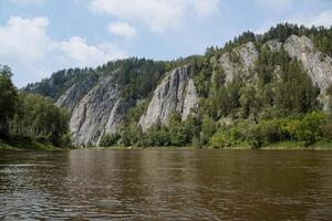 un' chiaro giorno su il fiume, grigio rocce In piedi di il acqua, un' montagna fiume con un' calma attuale, collinoso terreno, il meridionale urali di Russia, primavera tempo atmosferico. foto