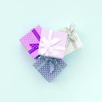 mucchio di un' piccolo colorato regalo scatole con nastri bugie su un' viola sfondo. minimalismo piatto posare superiore Visualizza foto