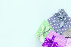mucchio di un' piccolo colorato regalo scatole con nastri bugie su un' viola sfondo. minimalismo piatto posare superiore Visualizza foto