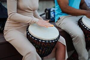 il ragazza giochi il tamburo djembe insieme con altro le persone, strada musicisti battere il ritmi di etno musica con loro mani. foto