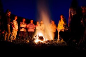 persone nel un' sfocato sfondo danza a notte di il fuoco, un' fuoco mostrare, danza con un' tamburello, sciamanico rituali nel natura, sera balli, un' grande fuoco di legna da ardere. foto